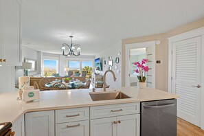 A kitchen with a sink, dishwasher, and dining area with chairs and a table.