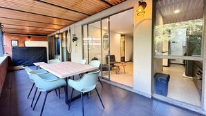 Een moderne eethoek met een houten plafond, een grote tafel en lichtgekleurde stoelen.