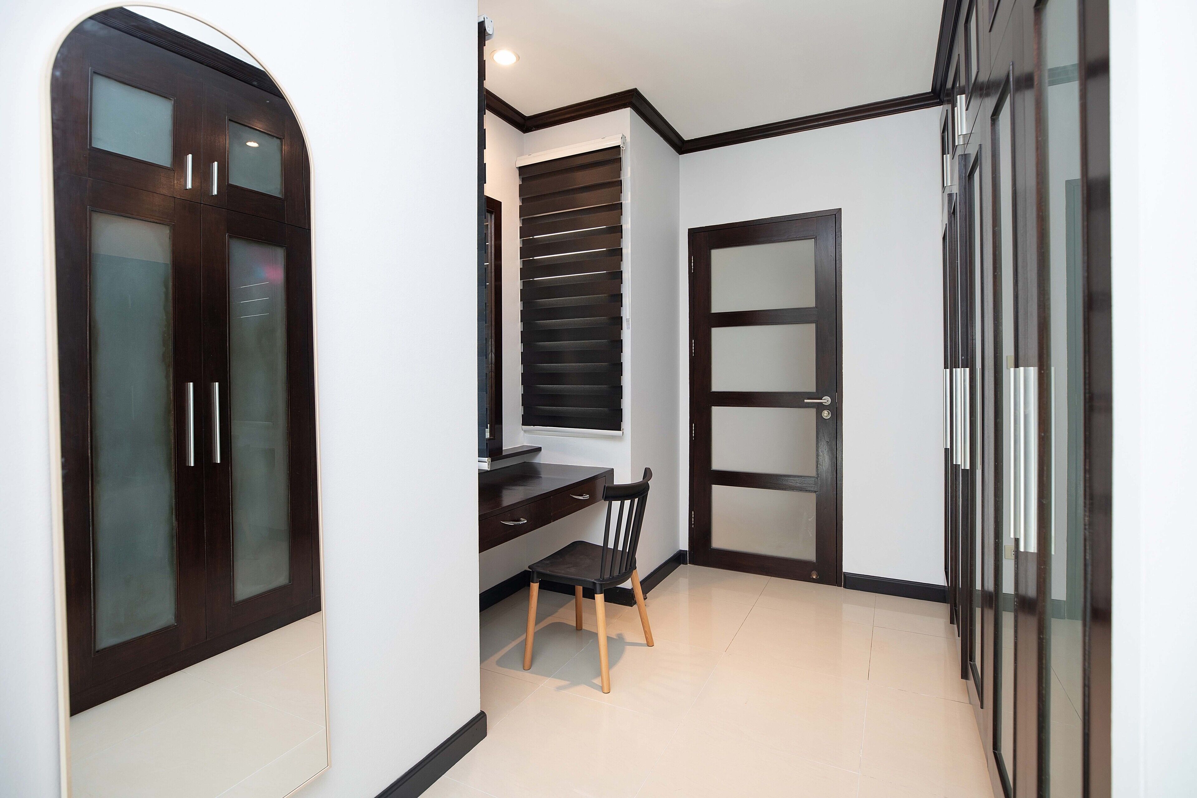 Une pièce comprenant un bureau, une chaise, une armoire et une fenêtre avec des stores.