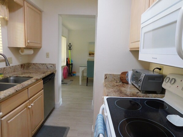 Una cocina compacta con estufa, microondas y lavabo.