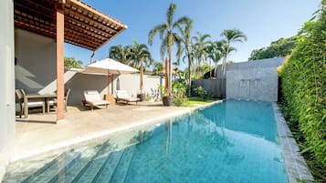 Una piscina al aire libre, sillones reclinables de piscina