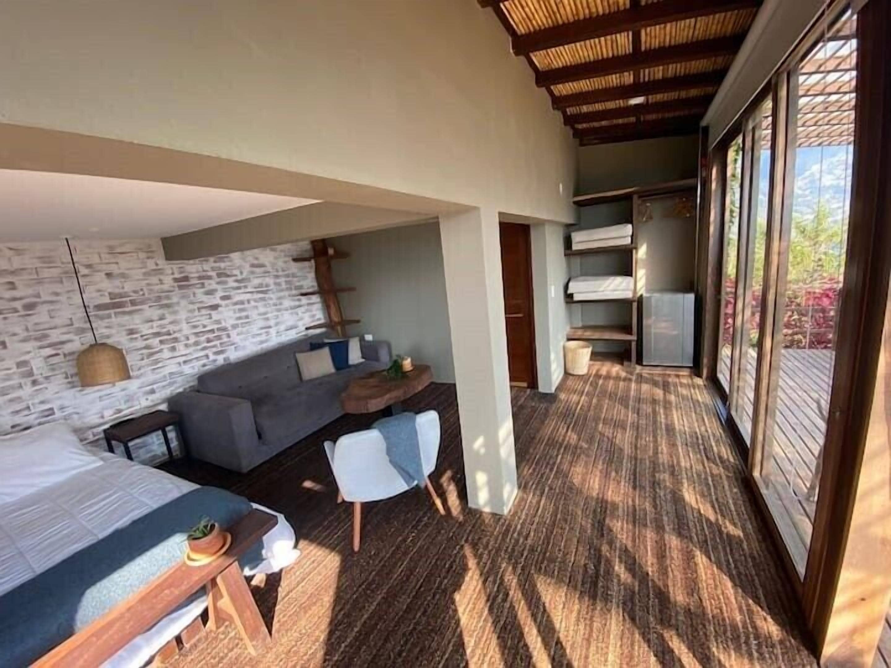 Una habitación moderna con pared de piedra, un sofá, un escritorio y una cama.