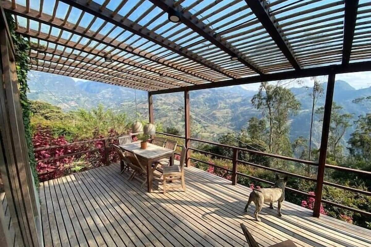 Een houten terras met een tafel en stoelen, met uitzicht op een bergachtig landschap.