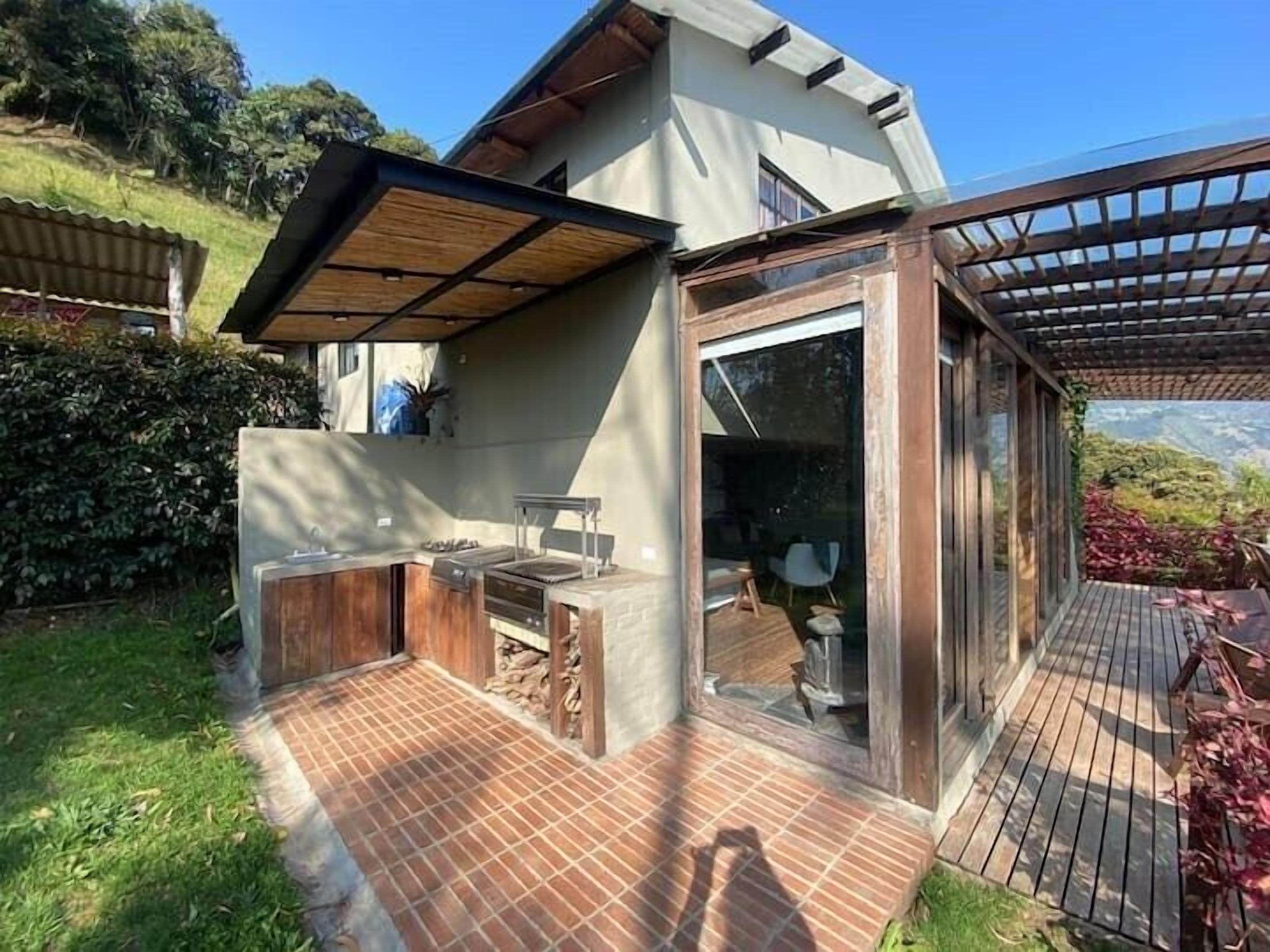 Une maison moderne dotée d’un patio, d’une cuisine extérieure et d’un espace couvert offrant une vue sur les montagnes.