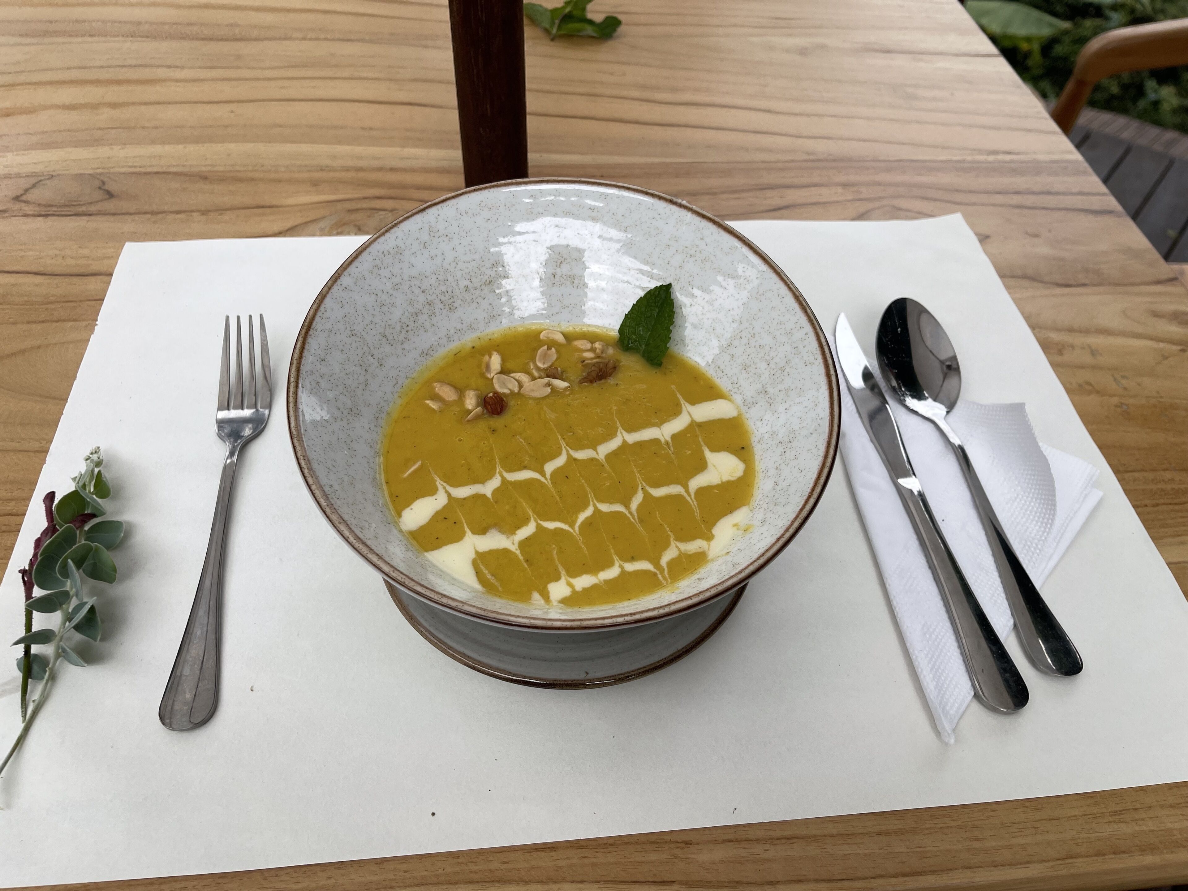 A bowl of soup on a white table with a fork and spoon on the left and right sides, respectively.