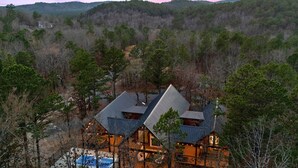 A large, modern lodge with multiple guest rooms, a swimming pool, and a scenic forest backdrop. - Luxe Pool Retreat for Couples and Small Groups (Broken Bow)