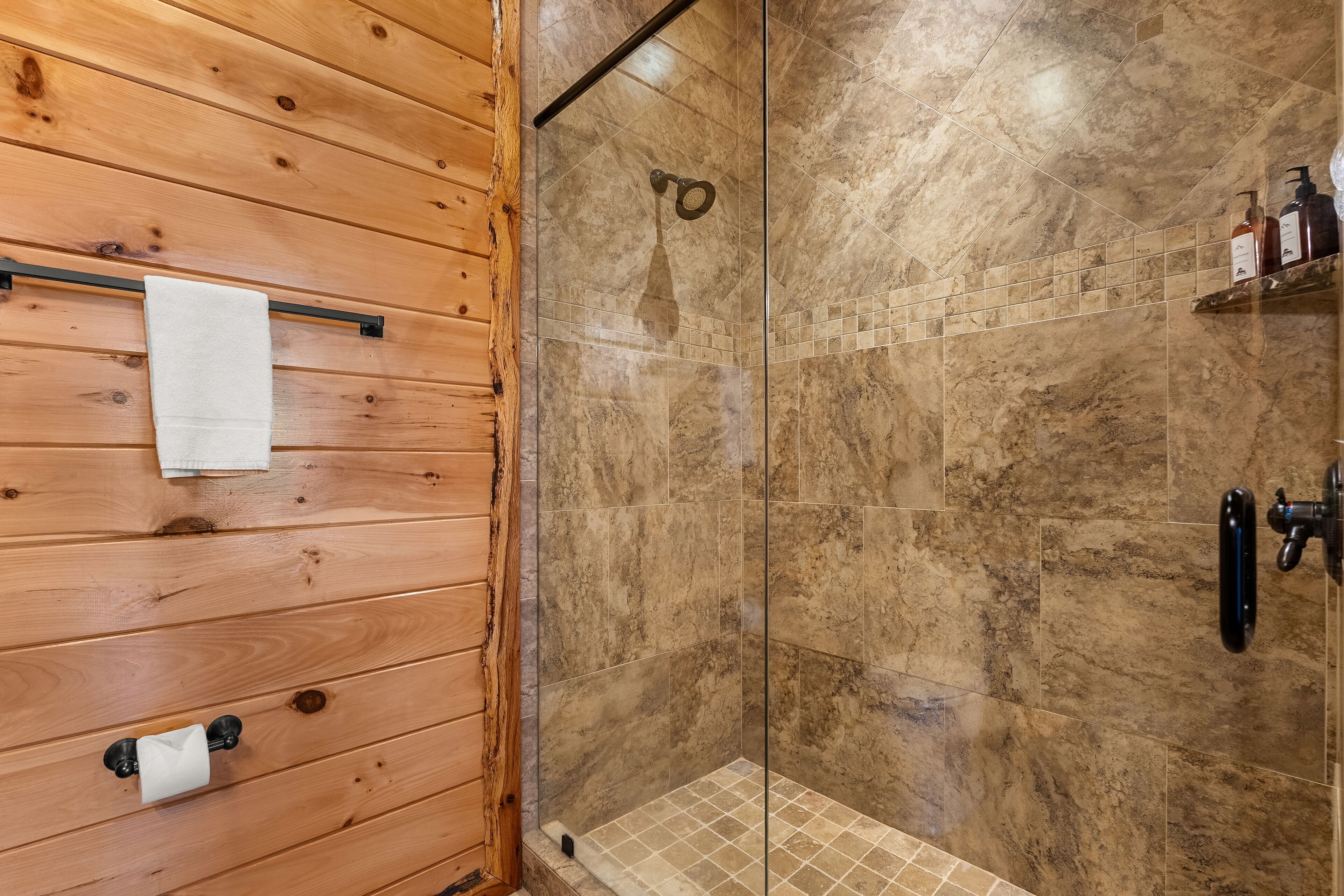 A wooden-paneled bathroom with a glass-enclosed shower area.