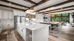 A spacious kitchen with white cabinetry, a large island, and a dining area with a view of the outdoors.