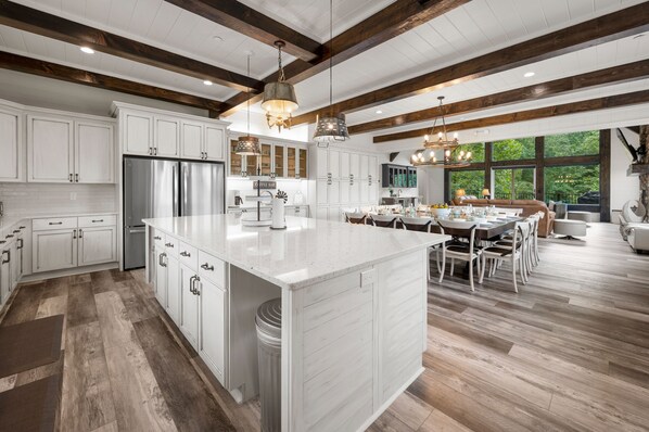 Una cocina amplia con armarios blancos, una isla grande y un comedor con vistas al exterior.