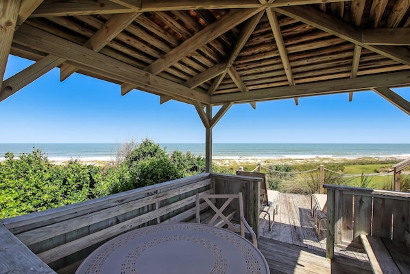 A wooden deck with a view of the beach and ocean.