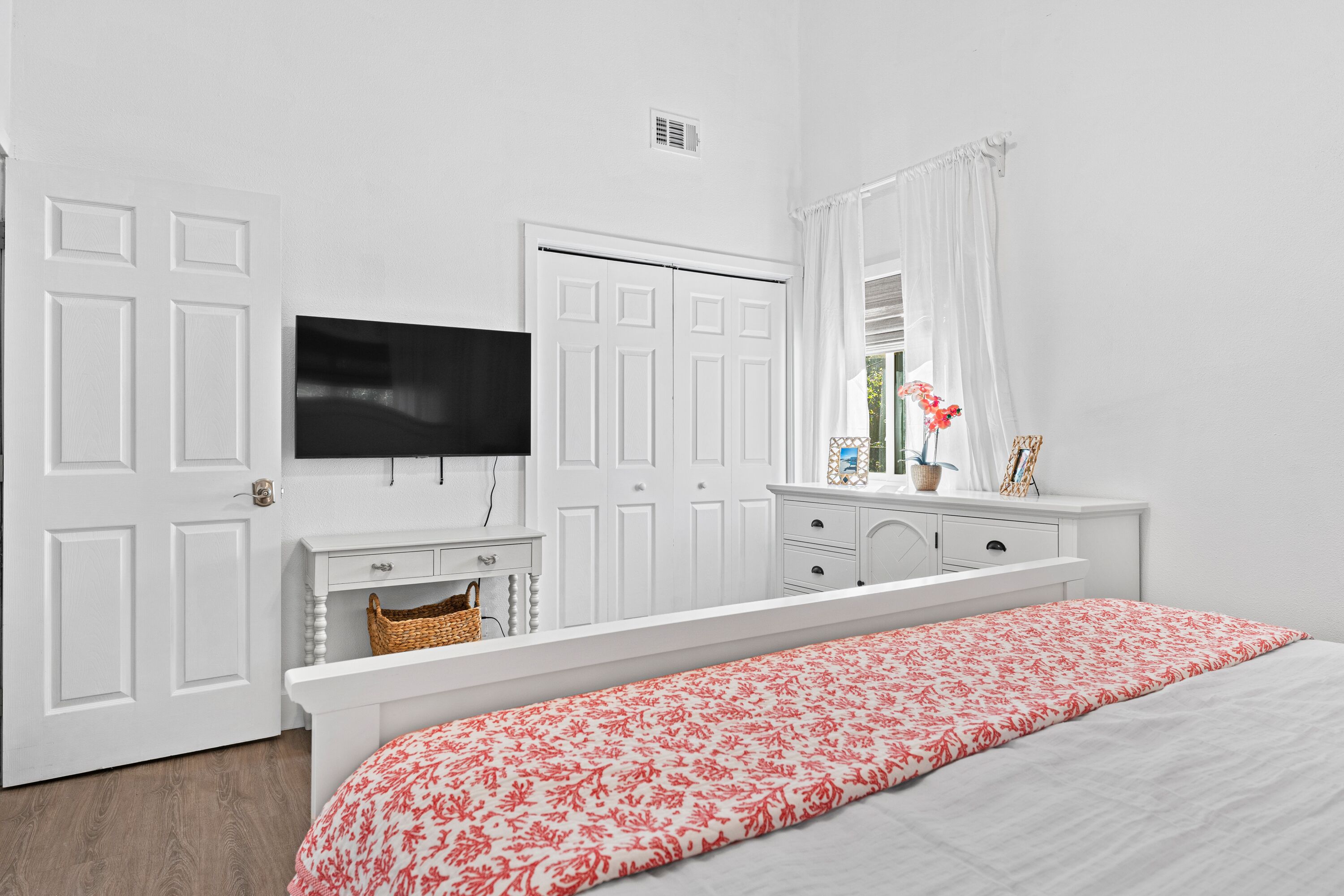 Una camera da letto con un letto, una TV a parete, un comò e un armadio.