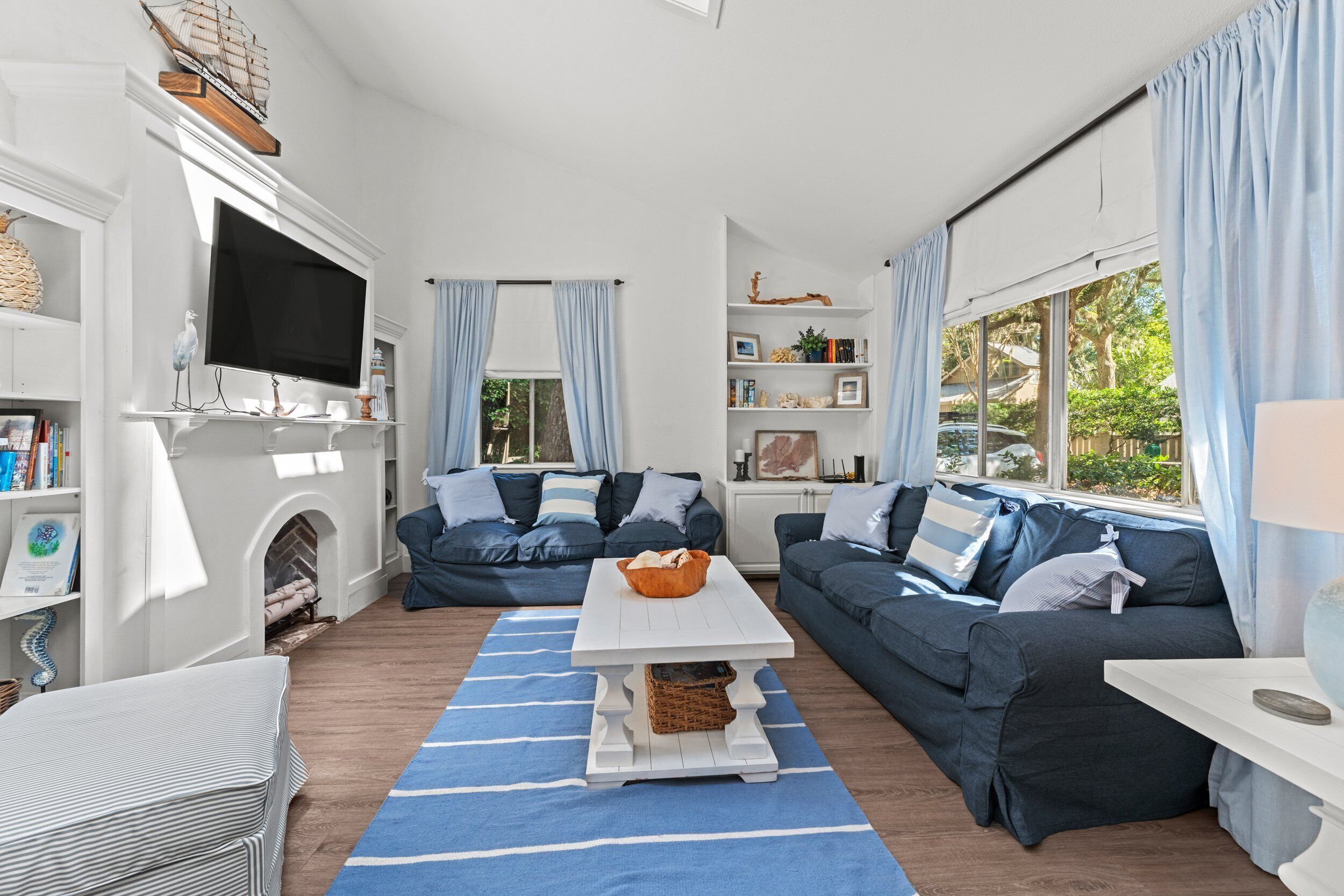 A modern living room with a fireplace, two sofas, a coffee table, and a TV mounted on the wall.
