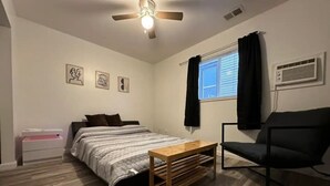 A bedroom with a bed, a wooden table, a chair, a ceiling fan, and a window with curtains. - Private 1 bed/1bath by Downtown Columbus, Arenas, & Hospitals (Columbus)