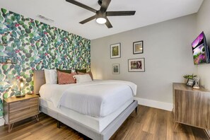 A bedroom with a bed, nightstand, and wall-mounted artwork.