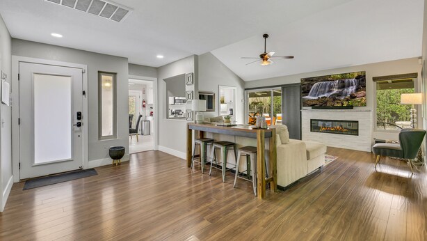 A spacious living area with a fireplace, a dining area with stools, and a large TV screen. - Bermuda Bliss: Pool, Spa, Misters, Ping Pong, BBQ! (Bermuda Dunes)