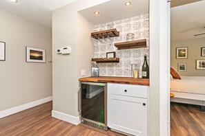 A compact kitchen with a dishwasher, wooden countertop, and decorative shelves.