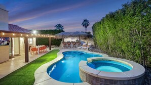 A backyard with a swimming pool, a hot tub, a covered patio with outdoor furniture, and a well-maintained lawn. - Bermuda Bliss: Pool, Spa, Misters, Ping Pong, BBQ! (Bermuda Dunes)
