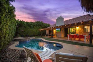 A backyard with a swimming pool, outdoor seating, and a TV screen. - Bermuda Bliss: Pool, Spa, BBQ! (Bermuda Dunes)