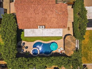 An aerial view of a residential property with a swimming pool, patio furniture, and a thatched umbrella. - Bermuda Bliss: Pool, Spa, BBQ! (Bermuda Dunes)