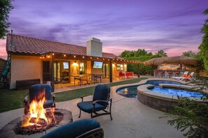 A backyard with a fire pit, outdoor seating, a pool, and a covered patio area.