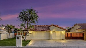 A residential house with a garage, a well-maintained lawn, and a tree. - Bermuda Bliss: Pool, Spa, Misters, Ping Pong, BBQ! (Bermuda Dunes)