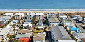Un quartier résidentiel situé sur la côte, avec des immeubles à plusieurs étages, une plage en arrière-plan et un ciel dégagé.
