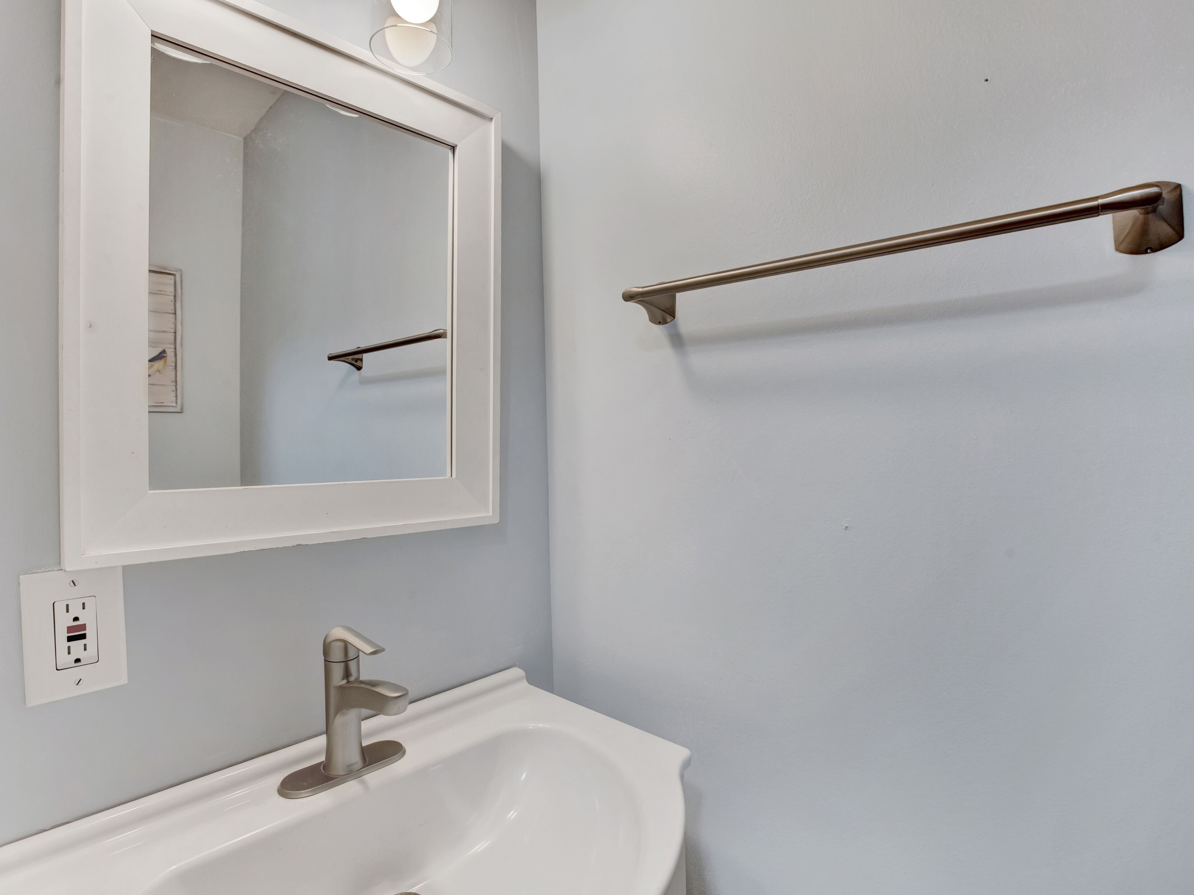 Une salle de bain avec un lavabo blanc, un miroir et un porte-serviettes.