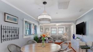 A dining area with wicker chairs, a wooden table, and a chandelier. - Entire Unit Steps from the Beach | Heated Pool Access (Tybee Island)
