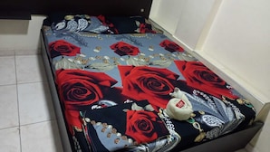 A bed with a floral bedspread featuring red roses and a small decorative pillow. - HOTEL ARCI (San José de Cúcuta)