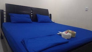 A bed with a blue bedspread and pillows, a white pillow with a red tag, and a small white bag on the bed. - HOTEL ARCI (San José de Cúcuta)