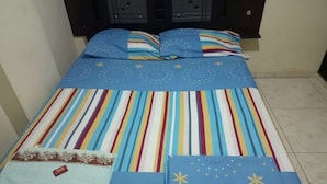 A bed with a striped bedspread and pillows, a folded blanket, and a small pouch with a tag. - HOTEL ARCI (San José de Cúcuta)