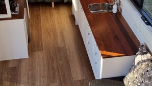 A compact, modern kitchen with a built-in stove, a sink, and a window overlooking a garden. - Tiny House/Retreat in Adelaide Hills. Secluded, peaceful, country views. (Macclesfield)