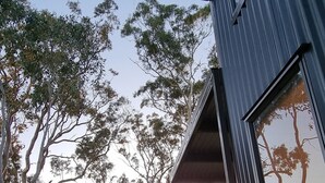 A modern building with a wooden deck, surrounded by a grassy area and trees. - Tiny House/Retreat in Adelaide Hills. Secluded, peaceful, country views. (Macclesfield)