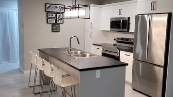 Una cocina moderna con una isla central, electrodomésticos de acero inoxidable y una zona de asientos tipo bar.