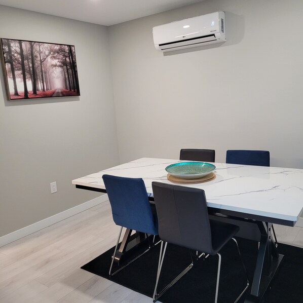 A modern dining area with a white table, blue chairs, and a glass bowl centerpiece.