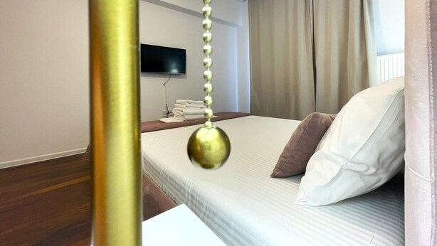 Une chambre d’hôtel avec un lit, un téléviseur fixé au mur et une table de chevet avec des serviettes.