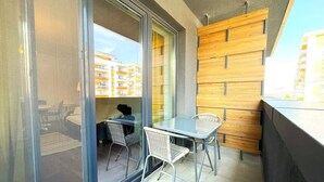 Un balcon avec une porte vitrée, des fauteuils en osier et une petite table.