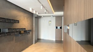 Un hall d’hôtel moderne au design minimaliste, comprenant un long comptoir d’accueil, un meuble de rangement fixé au mur et un mur d’accent en bois.