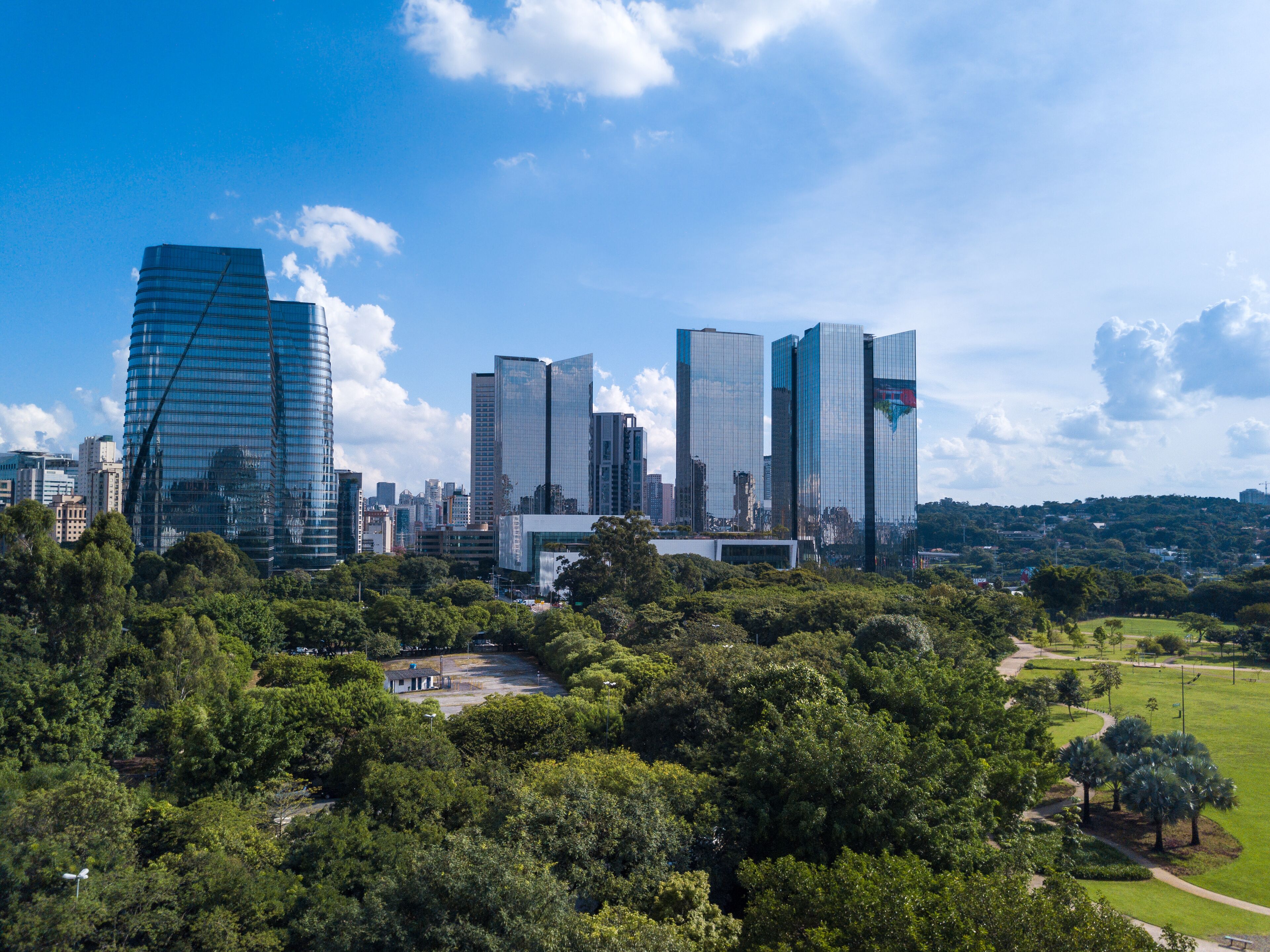 A cityscape with modern skyscrapers and a park area in the foreground.