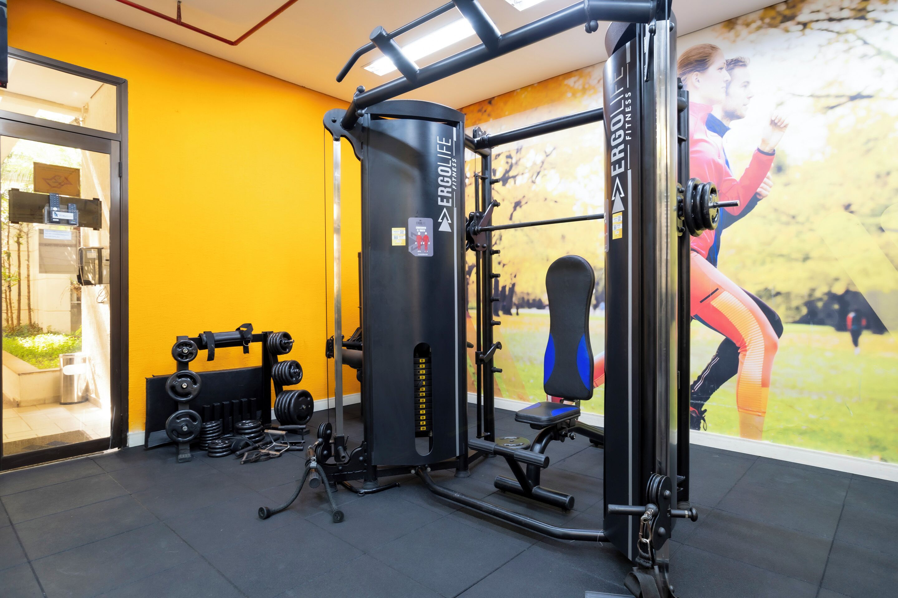 A gym with weightlifting equipment, a squat rack, and a bench.