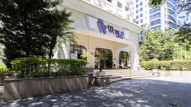A hotel entrance with a modern facade, a large entrance canopy, and a paved driveway.