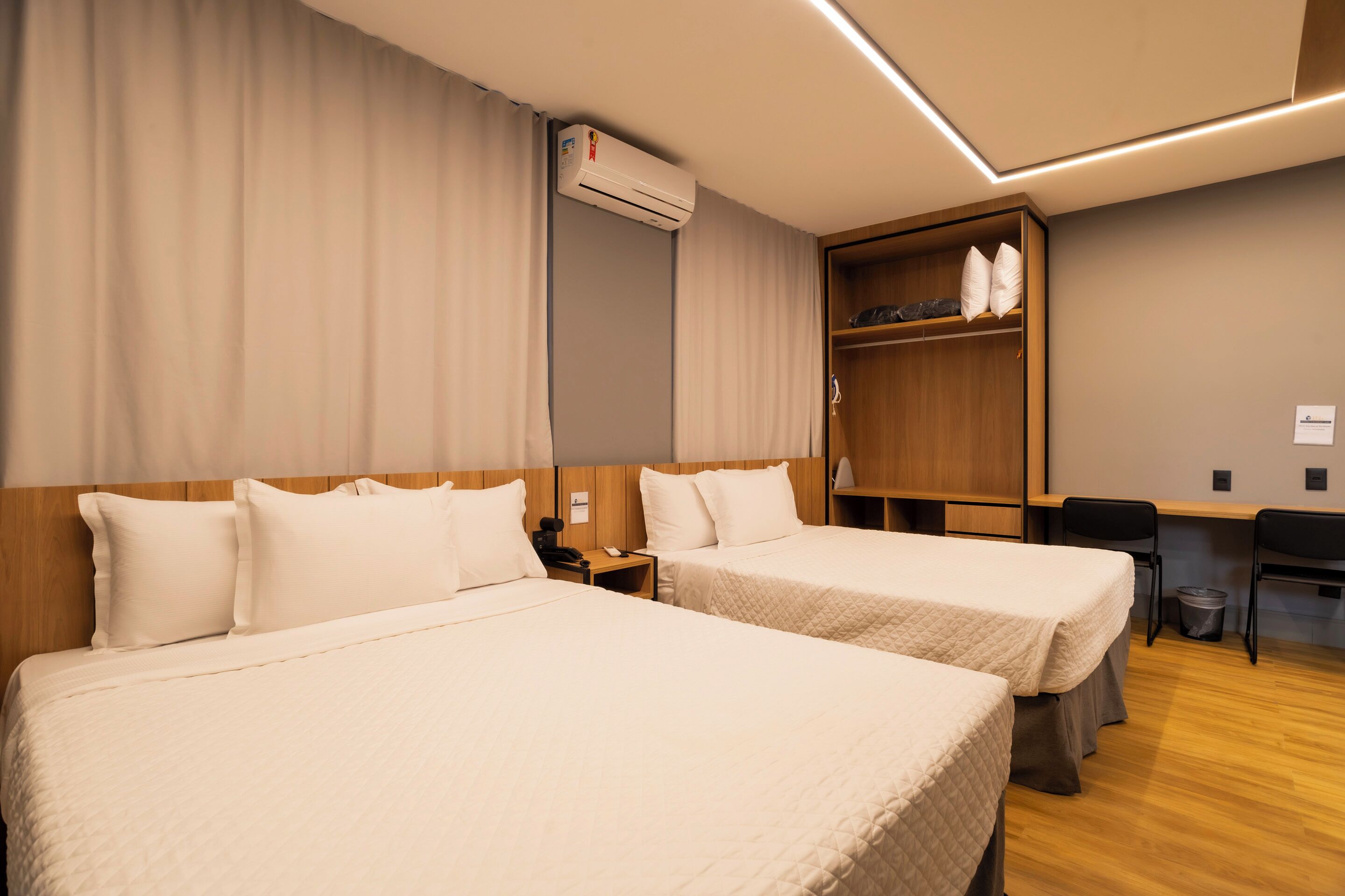 Une chambre d’hôtel avec deux lits, un bureau et une armoire.