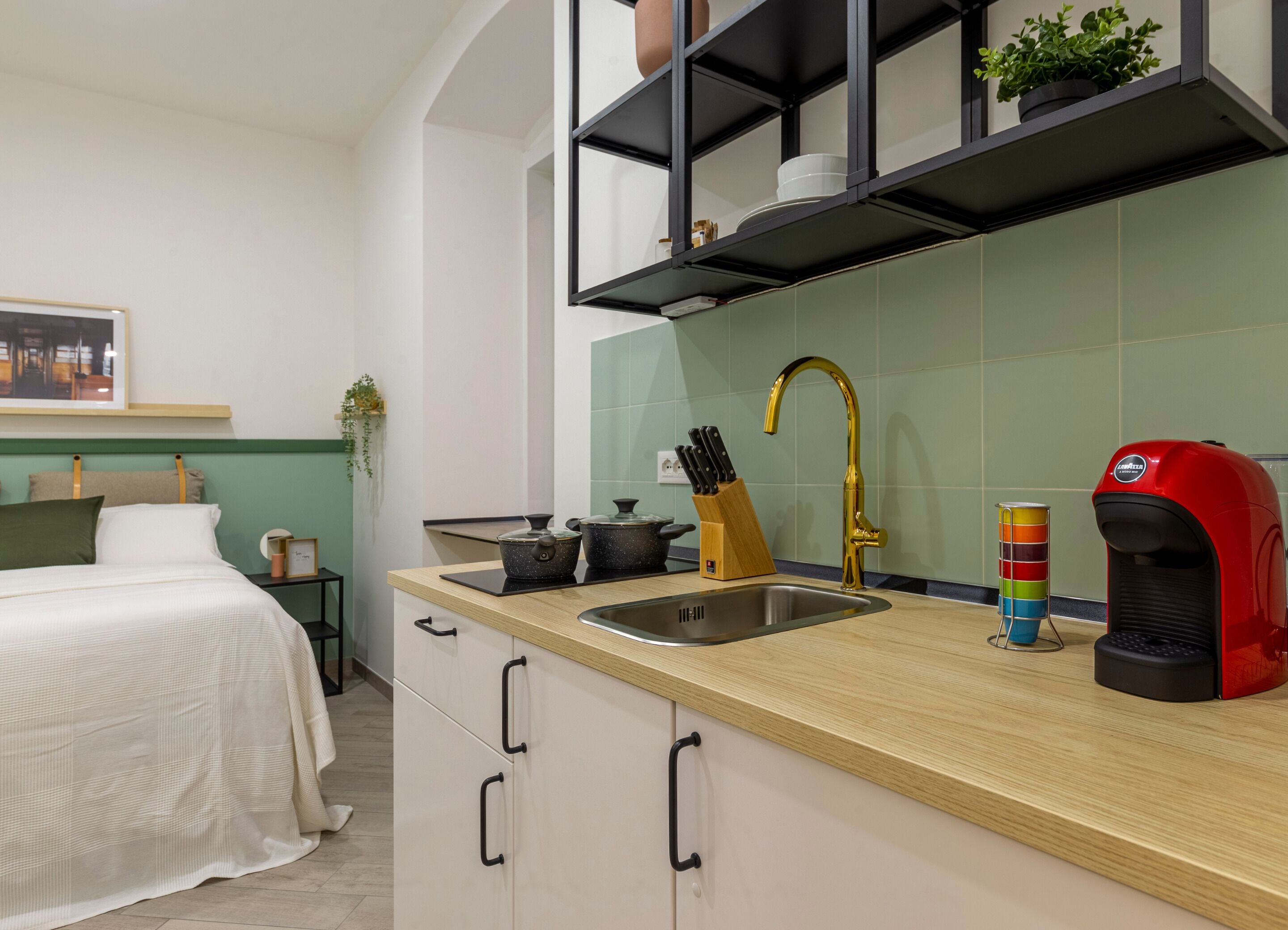 Eine moderne Küche mit Holzarbeitsplatte, Spüle aus Edelstahl, Armatur in Gold und einer roten Kaffeemaschine.