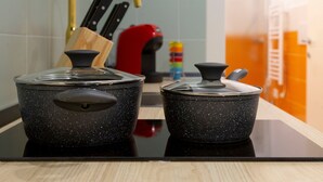 Two black speckled pots on a black countertop with a wooden cutting board and knives in the background. - Lovely and tiny unit in the City center (Trieste)