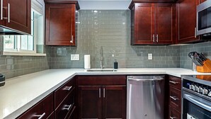 Una cocina moderna con armarios de madera oscura, lavavajillas de acero inoxidable y horno empotrado.