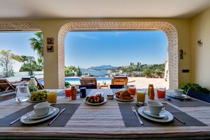 Enjoy breakfast with a view of the pool and coastal landscape from this dining area.