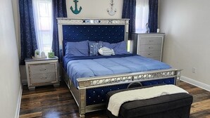 A bedroom with a bed, nightstands, a dresser, a ceiling fan, and wooden flooring. - Lux Home, Laplace (LaPlace)