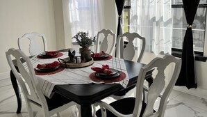 A dining area with a round table, white chairs, and a black tablecloth. - Lux Home, Laplace (LaPlace)