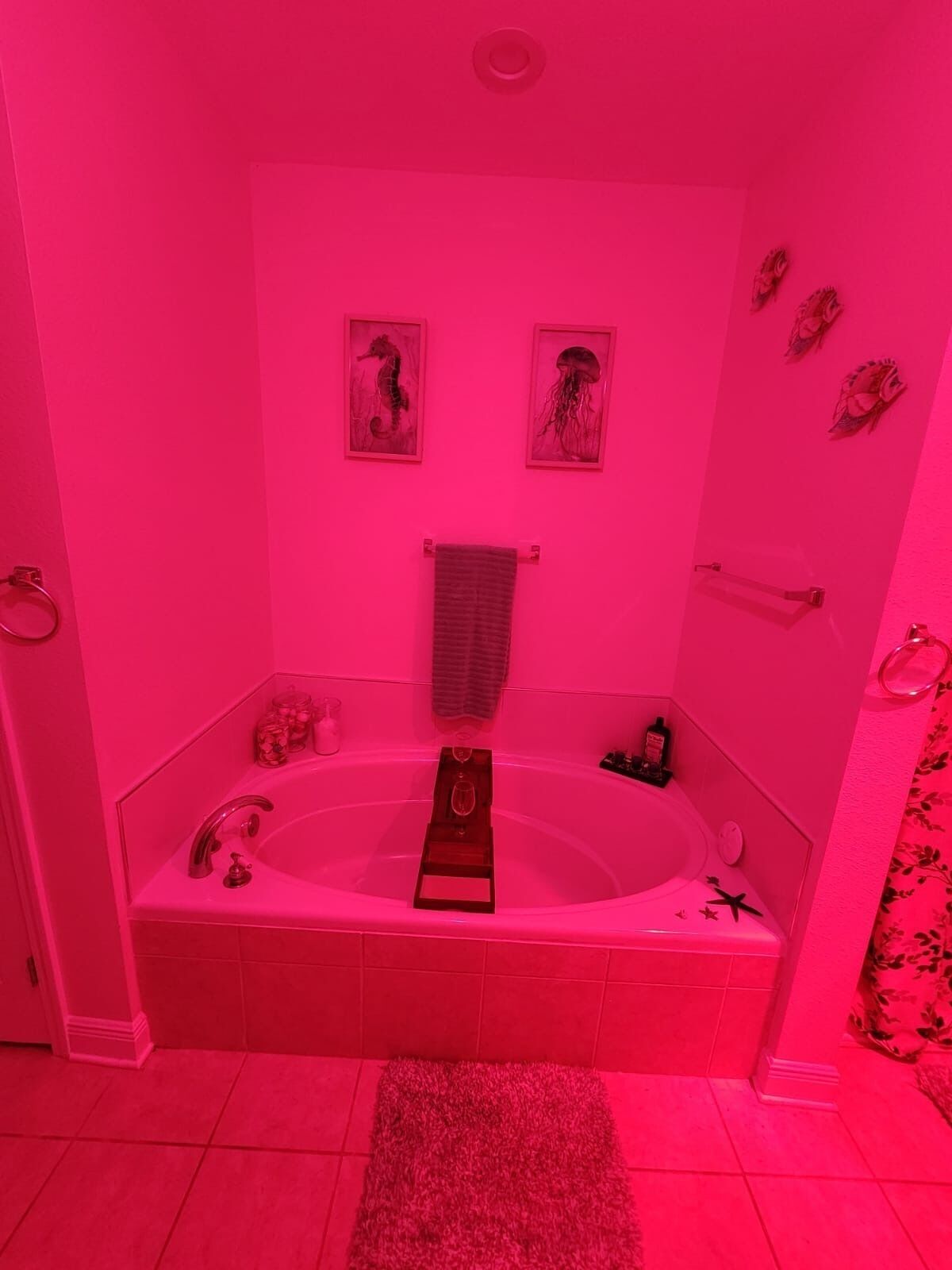 A bathroom with a large bathtub, a glass shower enclosure, and a pink color scheme.