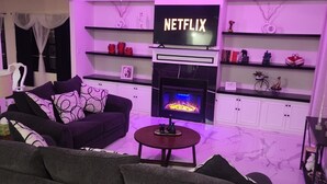 A living room with a fireplace, a TV mounted above it, and a ceiling fan. - Lux Home, Laplace (LaPlace)